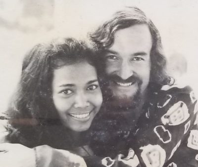 A black and white portrait of John as a young man, cheek to cheek with his wife